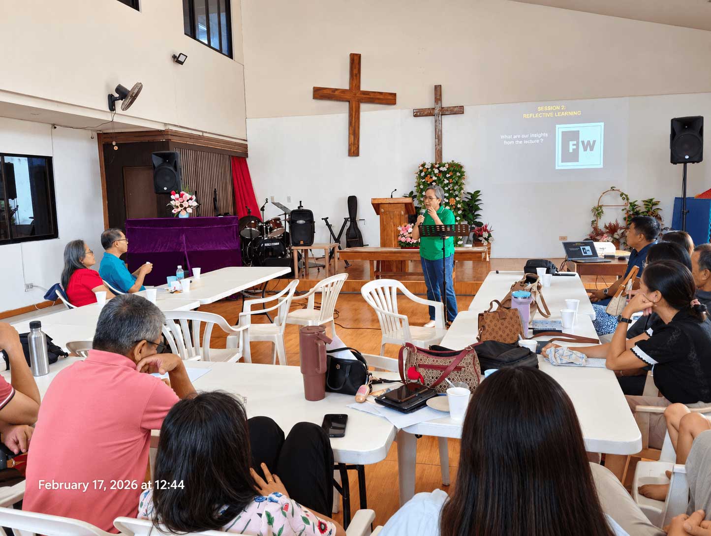 A class gathered in a bright room, listening to a teacher