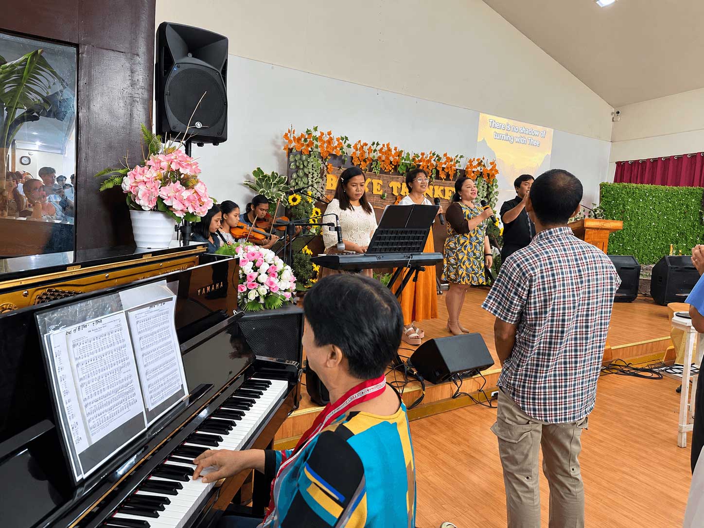 A worshipper with one hand raised under stage lights